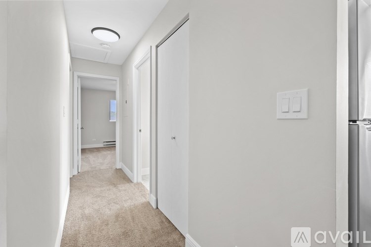 A long hallway with a carpeted floor and white walls.