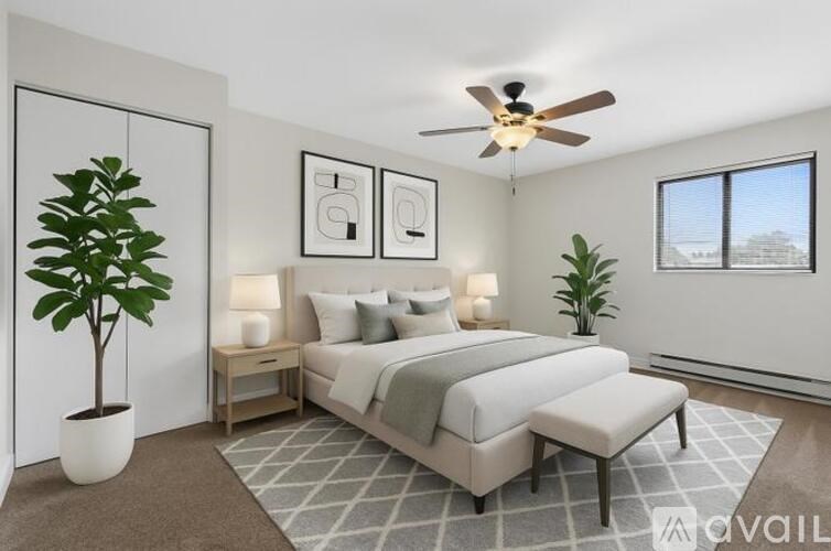 A bedroom with a bed, two lamps, a potted plant, and a ceiling fan.