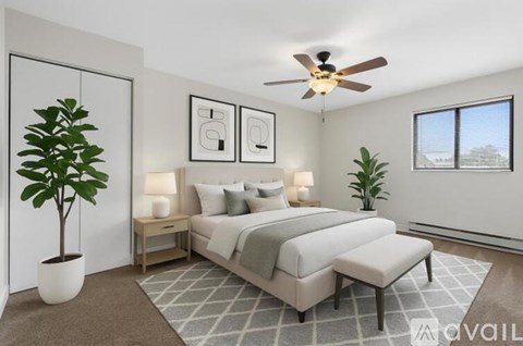A bedroom with a bed, two lamps, a potted plant, and a ceiling fan.
