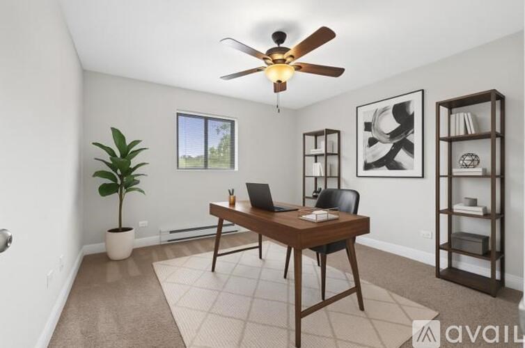 A room with a desk, chair, and a plant.