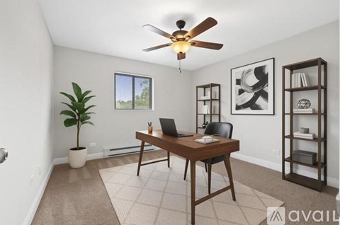 A room with a desk, chair, and a plant.