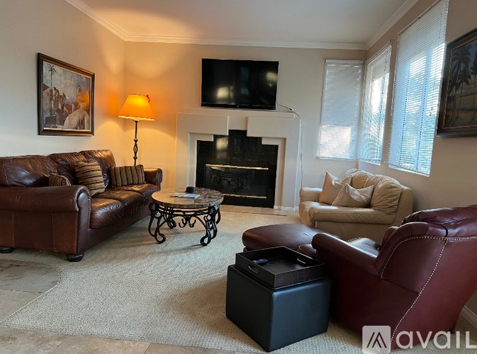A living room with a fireplace and a television mounted above it.