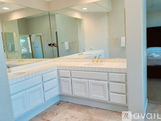 A bathroom with a large mirror, sink, and white cabinetry.