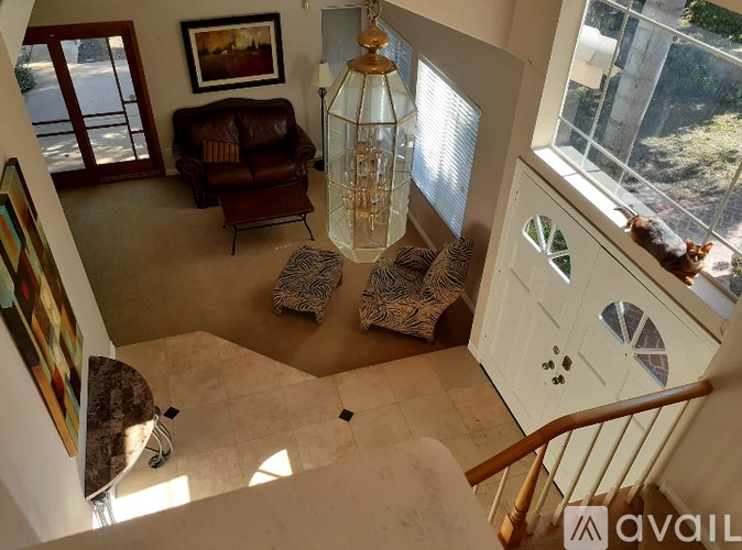 A living room with a brown leather couch and a painting on the wall.