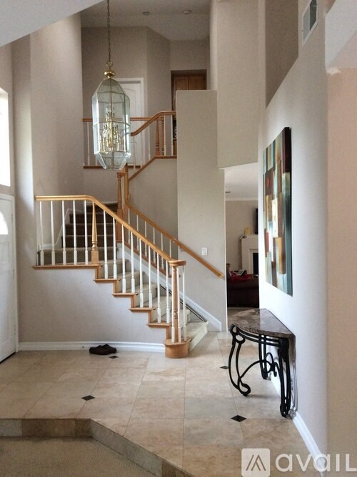 A staircase with a glass railing and a hanging light fixture.
