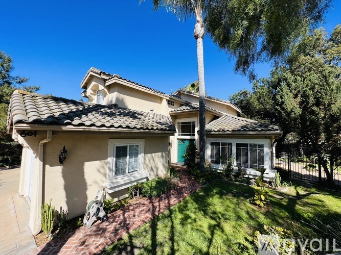 A house with a green door and a red brick pathway in front.