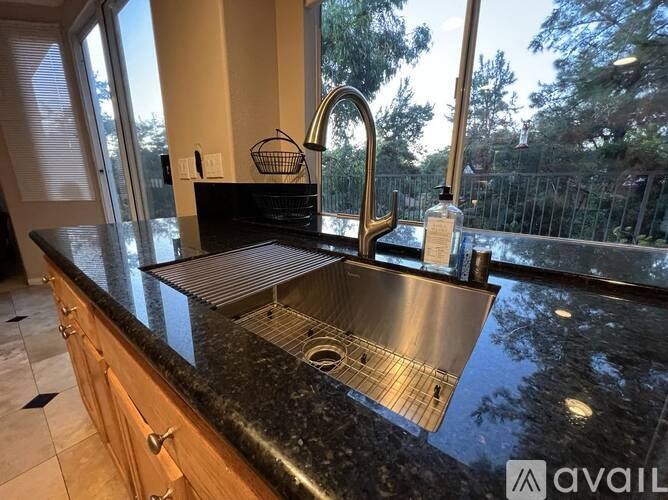 A kitchen with a black granite countertop and a stainless steel sink.