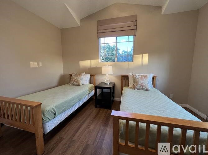 A bedroom with two beds and a nightstand.