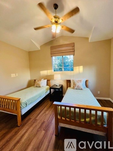 A bedroom with two beds and a ceiling fan.