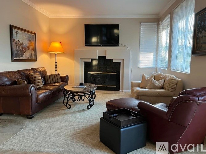 A living room with a fireplace and a television mounted above it.