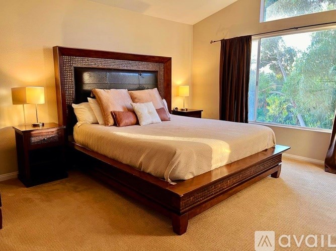 A bedroom with a large bed and two lamps.