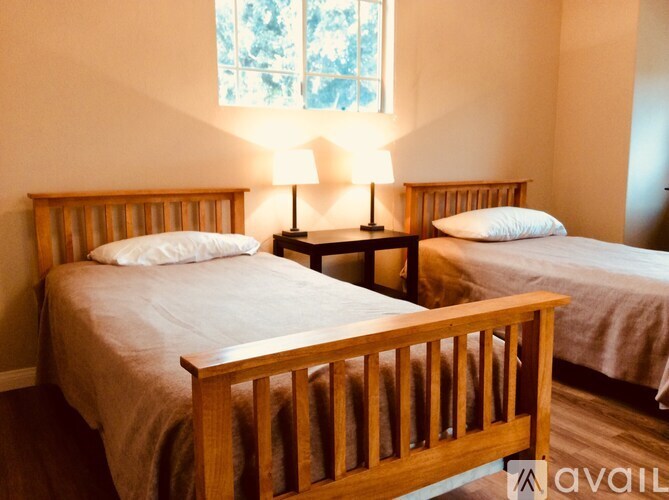 Two beds with white pillows and wooden headboards in a room.