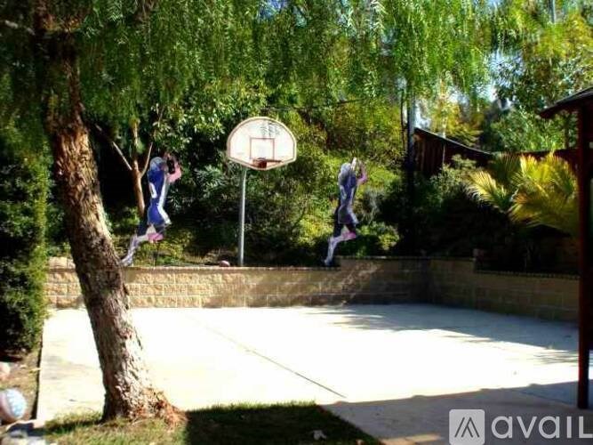 Two people playing basketball in a backyard.