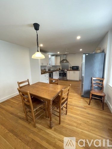 A kitchen with a table and chairs in the foreground and a refrigerator in the background.