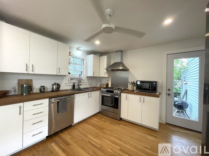 A kitchen with white cabinets and wooden floors.