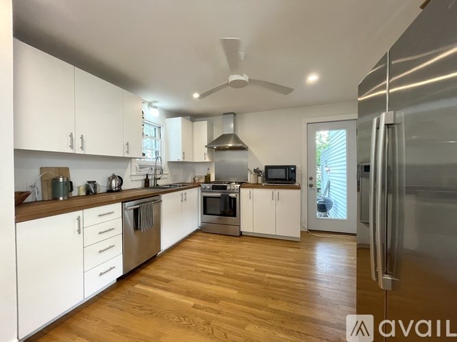 A modern kitchen with wooden floors and stainless steel appliances.