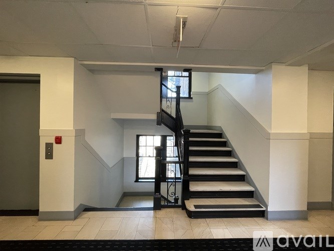 A staircase with a black railing and steps leading up to a window.