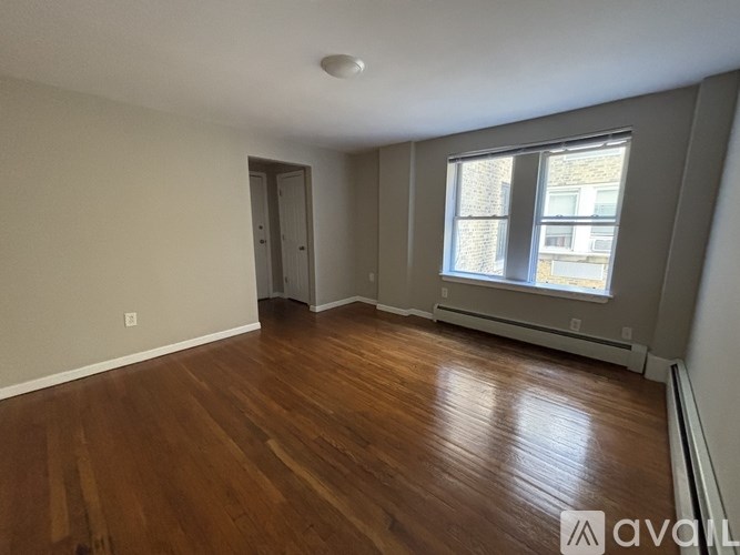 A room with wooden floors and a window with a view of a building outside.