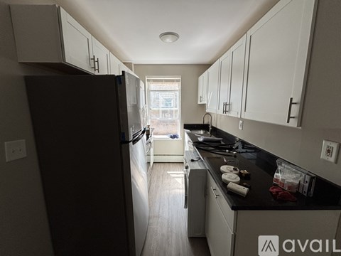 A kitchen with a black refrigerator and white cabinets.