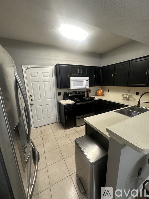 A kitchen with black cabinets and a white fridge.