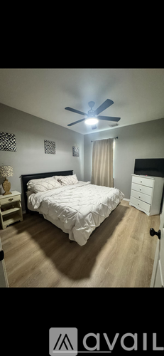 A bedroom with a bed, dresser, and ceiling fan.