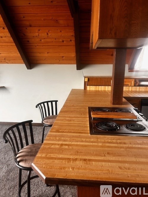 A wooden table with a stove on top and chairs around it.