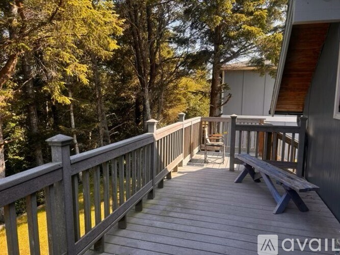 A wooden deck with a bench and a table surrounded by trees.
