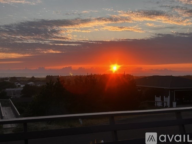 A sunset view from a balcony with the sun partially obscured by clouds.