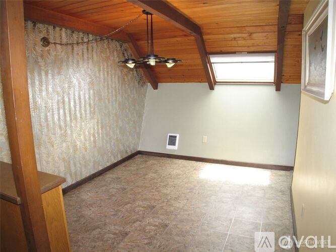 A room with a wooden ceiling and a window with light coming through.