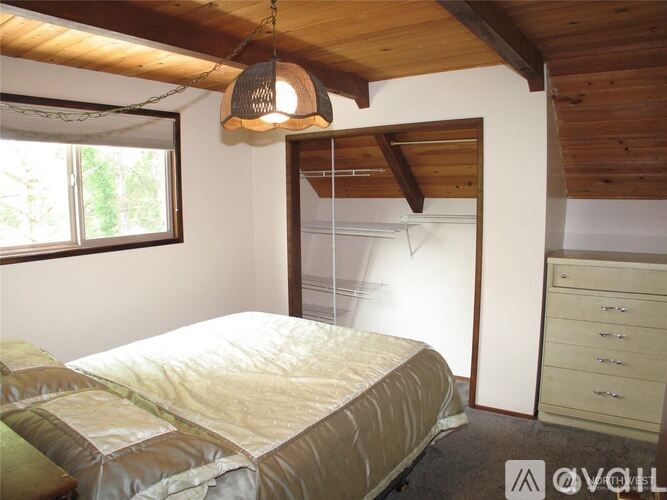 A bedroom with a bed, dresser, and a window.