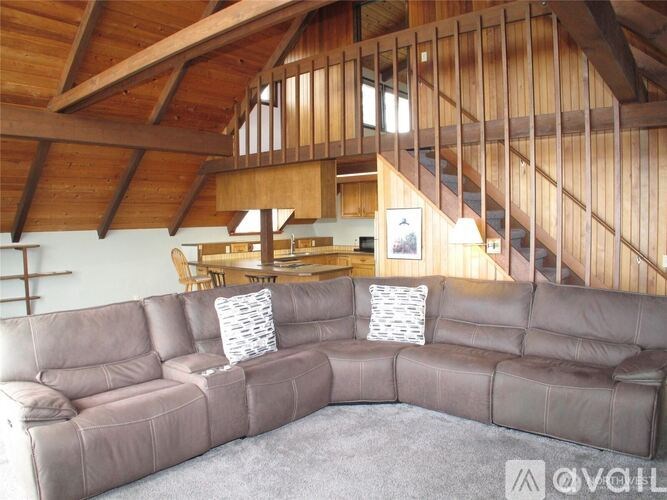 A grey sectional sofa with a wooden ceiling and staircase in the background.