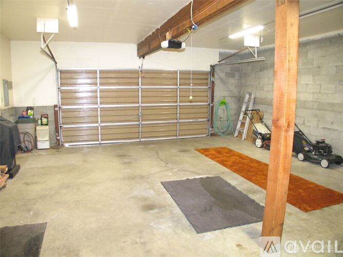 A garage with a brown mat on the floor and a black vacuum cleaner.