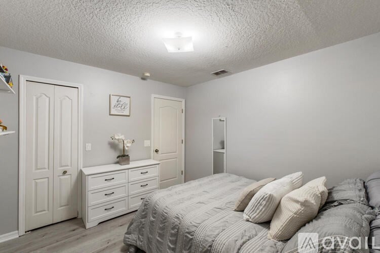 A bedroom with a bed, dresser, and nightstand.
