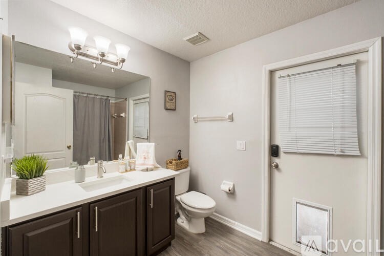 A bathroom with a white countertop and brown cabinets.