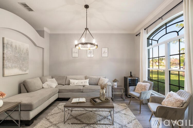 A living room with a grey sofa, a coffee table, and a large window.