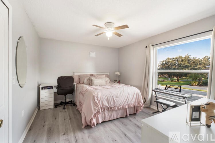 A bedroom with a bed, chair, and a window overlooking a park.