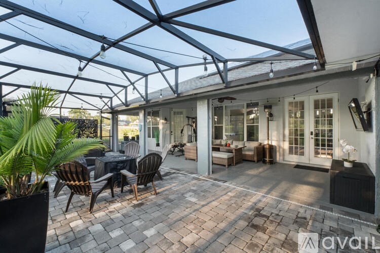 A patio with a table set for dining under a glass roof.