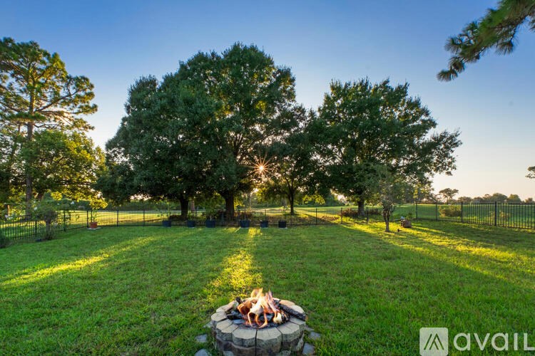 A group of people sitting around a fire pit in a grassy field.