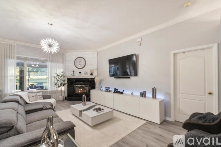 A living room with a grey couch, a white coffee table, and a flat screen TV mounted on the wall.