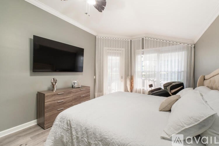 A bedroom with a large bed, a flat screen TV, and a wooden dresser.