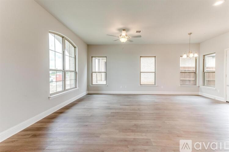 A spacious room with wooden floors and large windows.