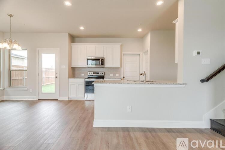 A modern kitchen with white cabinets and a wooden floor.