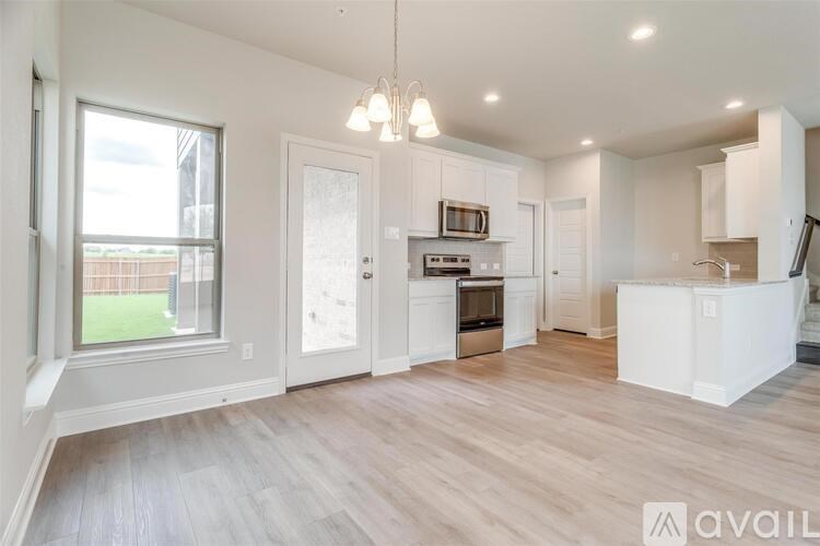 A spacious kitchen with white cabinets and a wooden floor.