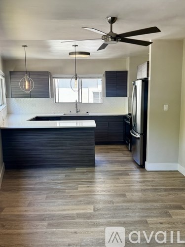 A kitchen with a black counter top and a ceiling fan.