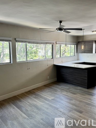 A room with a ceiling fan and a large window.