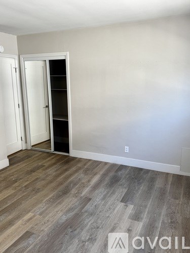 A room with a wooden floor and two open doors.