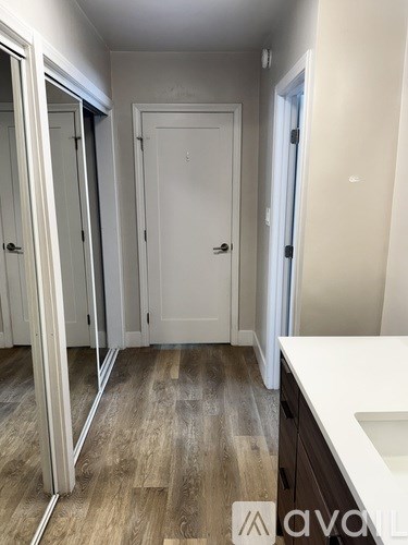 A white door is in the middle of a room with wood flooring.