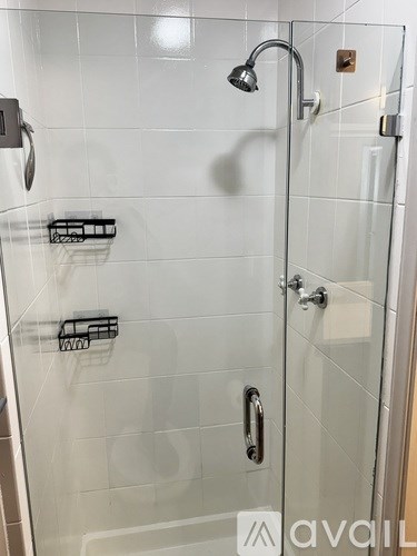 A shower with a glass door and a silver handle.