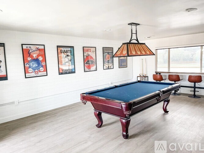 A pool table in a room with a light colored wall and a hanging light fixture.