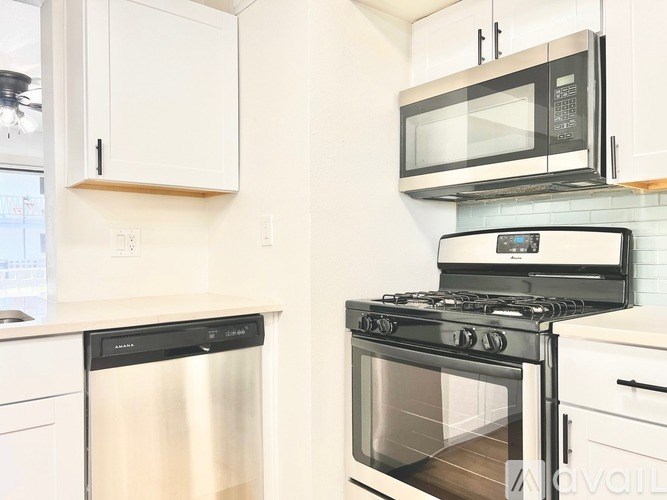 A modern kitchen with a stainless steel dishwasher and a black stove top oven.
